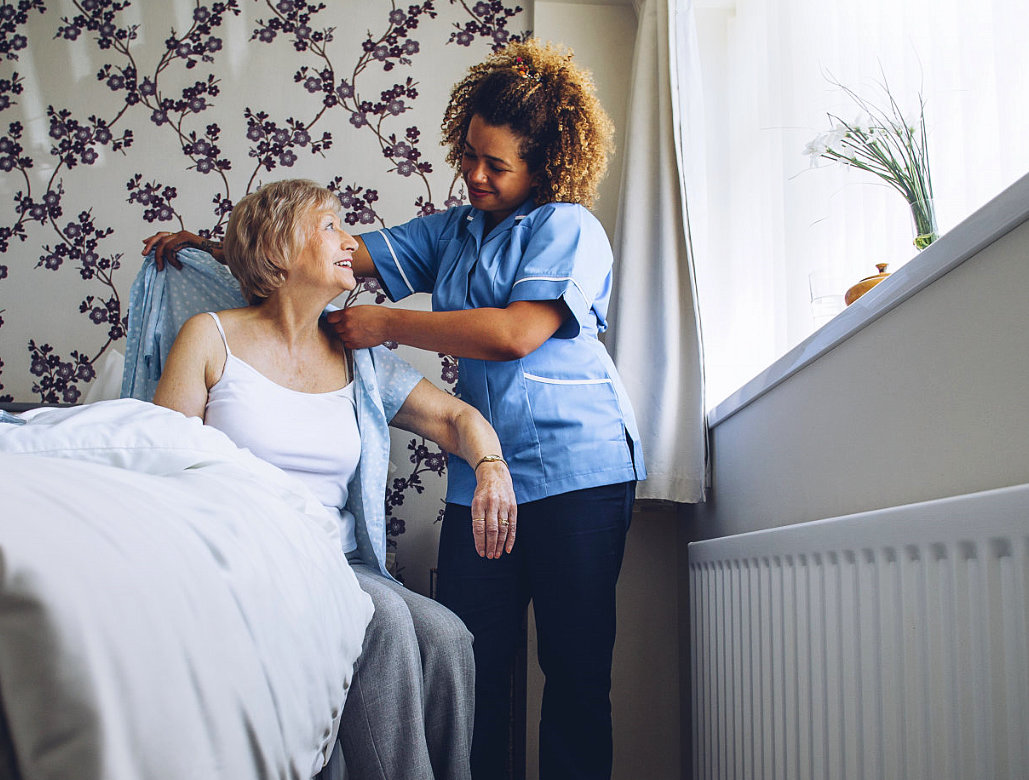 Home caregiver helping a senior women get dressed in her bedroom