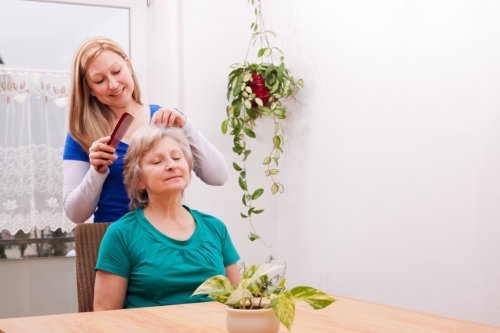 caregiver combing an elderly woman's hair
